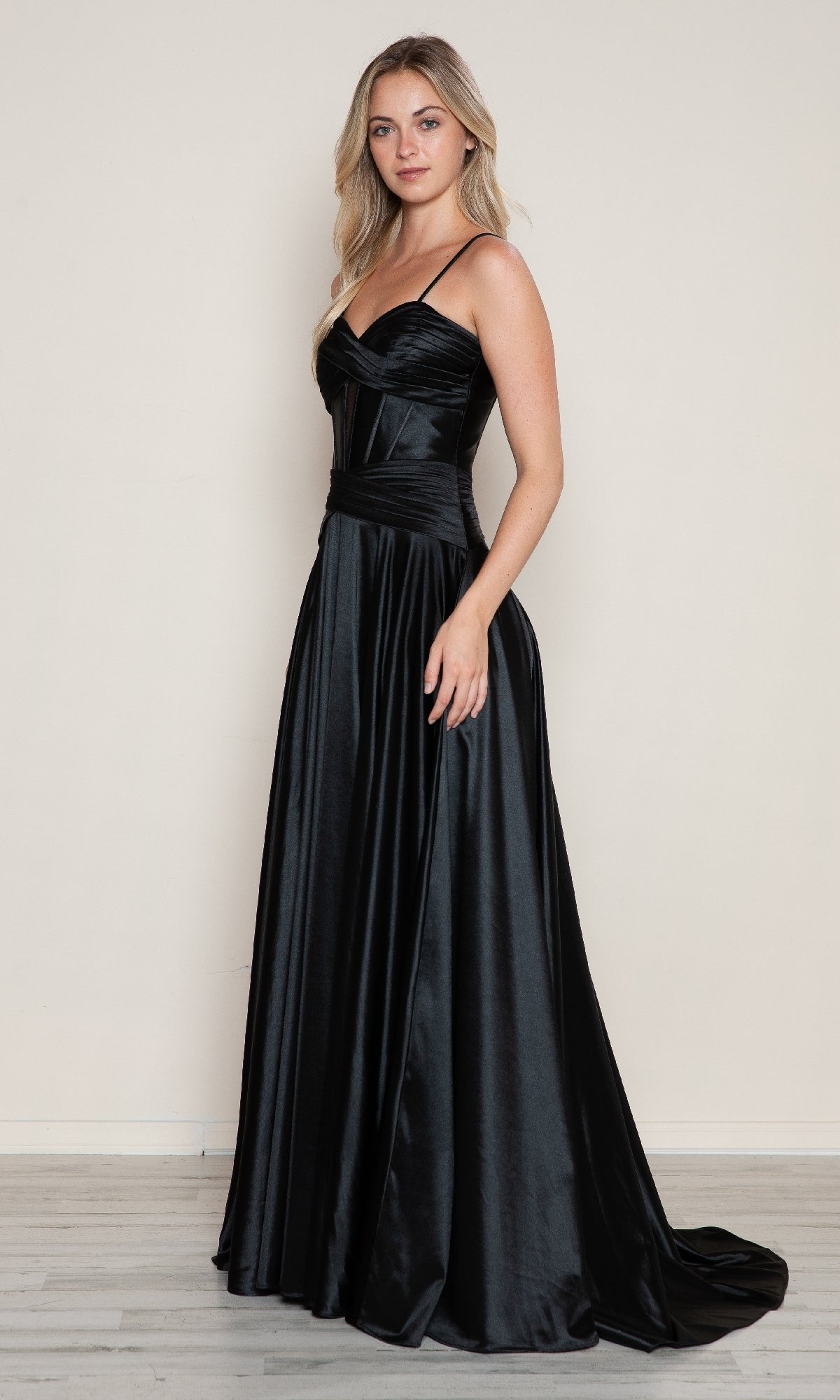 A woman stands in front of a plain light-colored wall wearing the Poly USA 9700 Cut-Out Long A-Line Prom Dress in black.